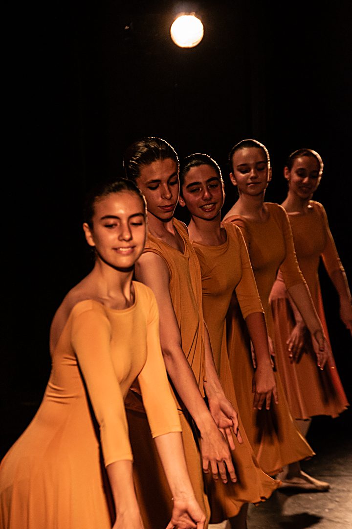 Fila d'alumnes de ballet amb vestits taronja ballant a l'escenari del festival de fi de curs