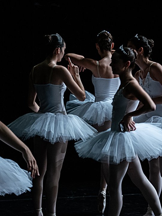 Alumnes avançades de ballet amb tutús blancs de cignes esperant el seu torn a l'escenari