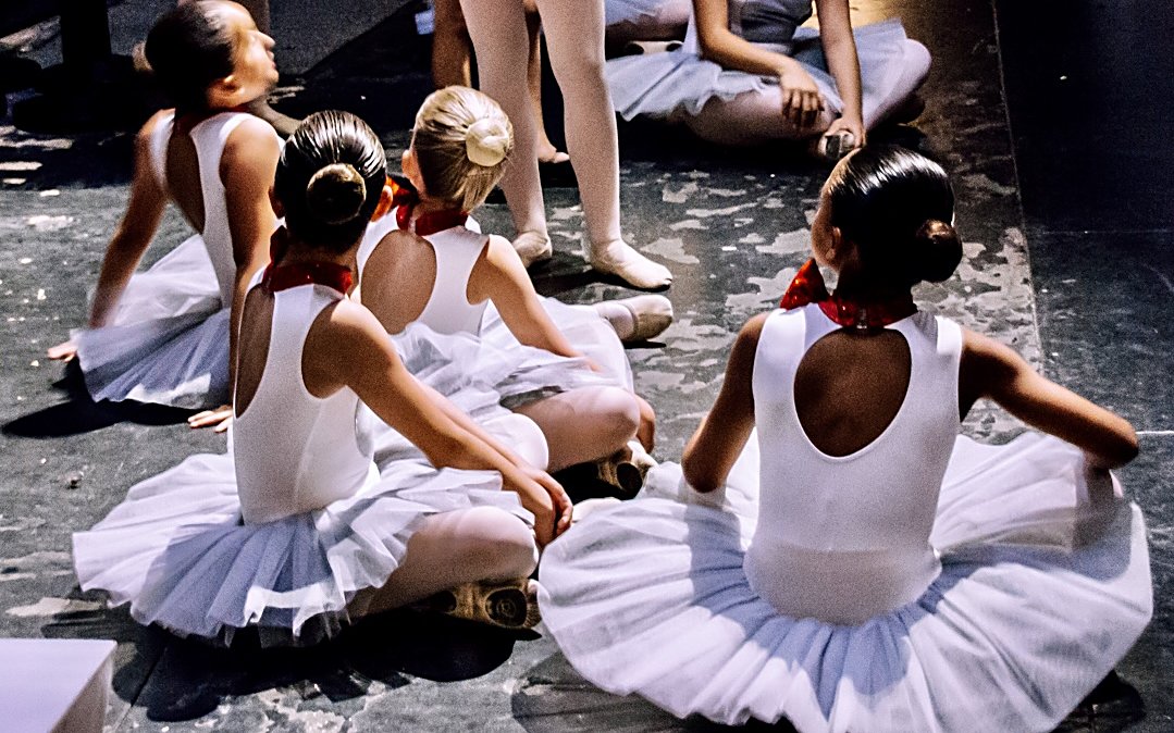 Nenes de ballet infantil amb tutús blancs assegudes a l'escenari del teatre, abans d'actuar