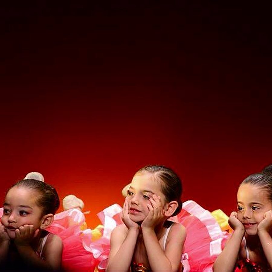 Nenes de ballet infantil assegudes a l'escenari amb vestits vermells al festival de fi de curs